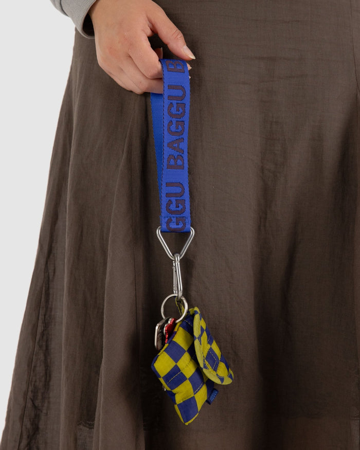 Royal blue coloured webbed material logo keychain with BAGGU branding attached to earbuds case and keys.