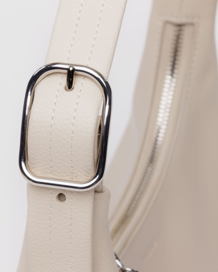 Close up of silver buckle hardware on adjustable shoulder strap of mini recycled leather bag in stone