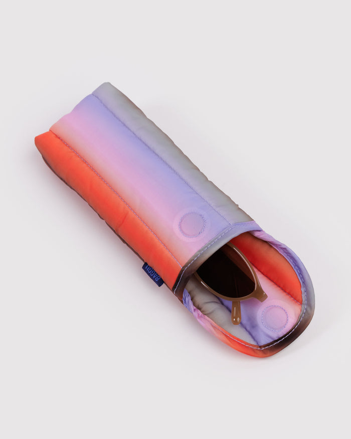 Gradient-coloured sunglasses case open with sunglasses inside and magnetic closure with BAGGU logo tag.