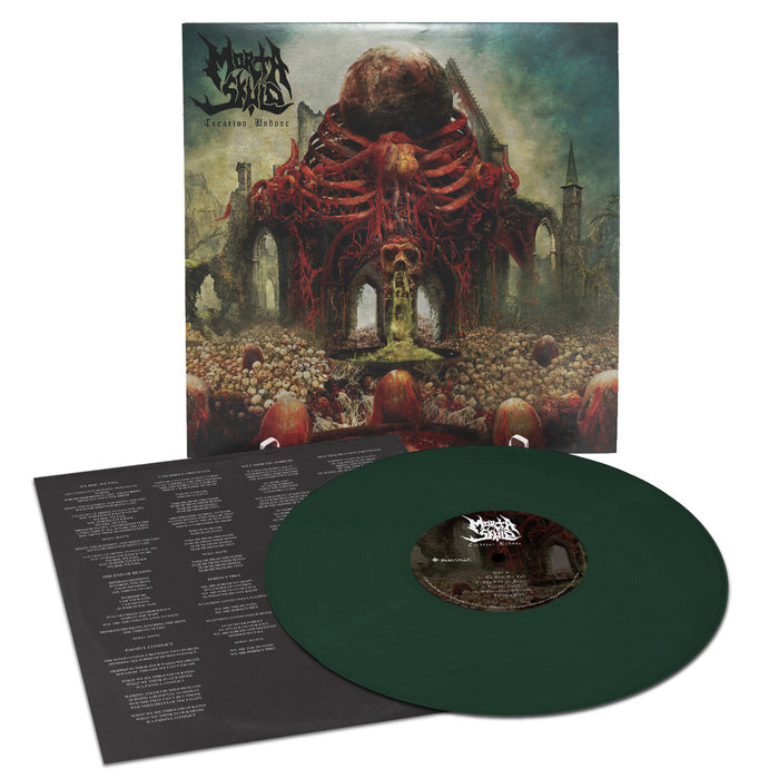 A dark green MORTA SKULD vinyl and lyric sheet sit before an album cover depicting a grotesque red organic structure with skulls and arches, embodying the apocalyptic style of the US death metal legends.