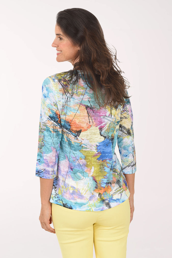 Woman wearing a colorful abstract patterned top with yellow pants on a white background