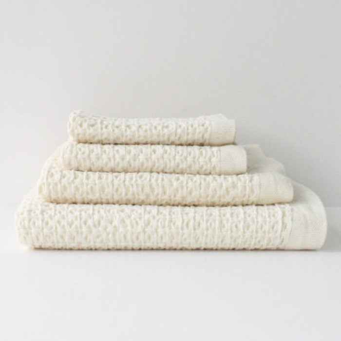 Stack of folded ivory waffle textured towels.
