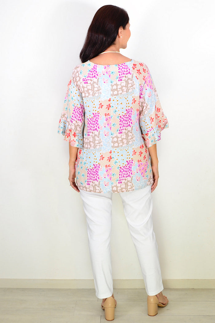 Relaxed soft floral Wishstone tunic top hanging on a hanger, featuring a flowy silhouette and vibrant floral pattern.