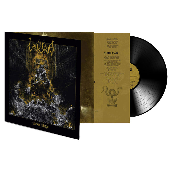 A VALKYRJA vinyl record is partially pulled from its sleeve, showing cover art of a crowned skeletal figure on a burning throne amid writhing bodies. The gold inner sleeve displays printed lyrics.