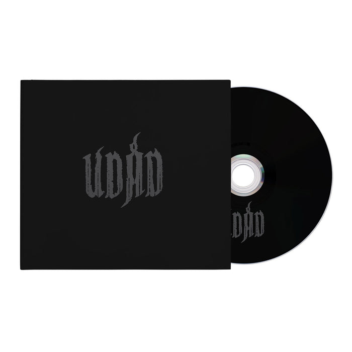 A black CD slips into a matching black case, both branded with "Udåd" in stylized dark gray letters. The minimalist design and plain white background evoke the raw aesthetic of black metal.