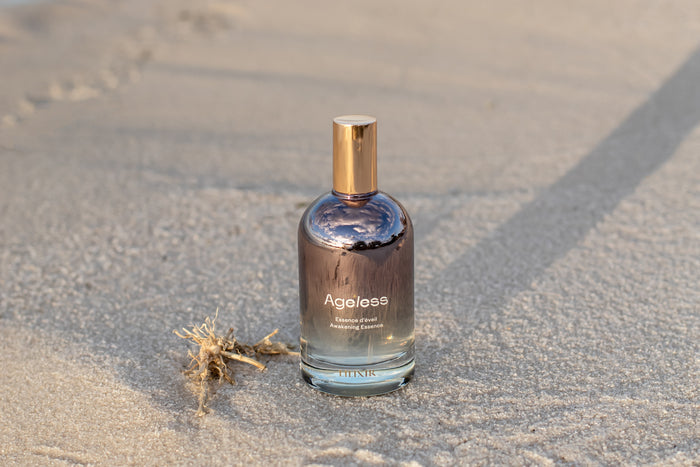 Bottle of 'Ageless' essence on a sandy surface