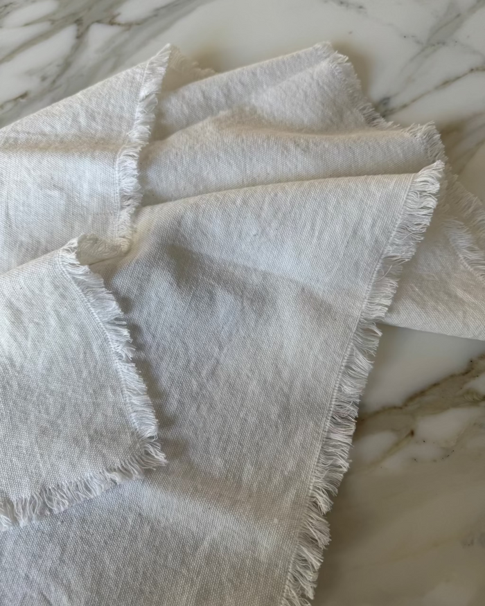 White cotton napkin with frayed edges on a marble surface