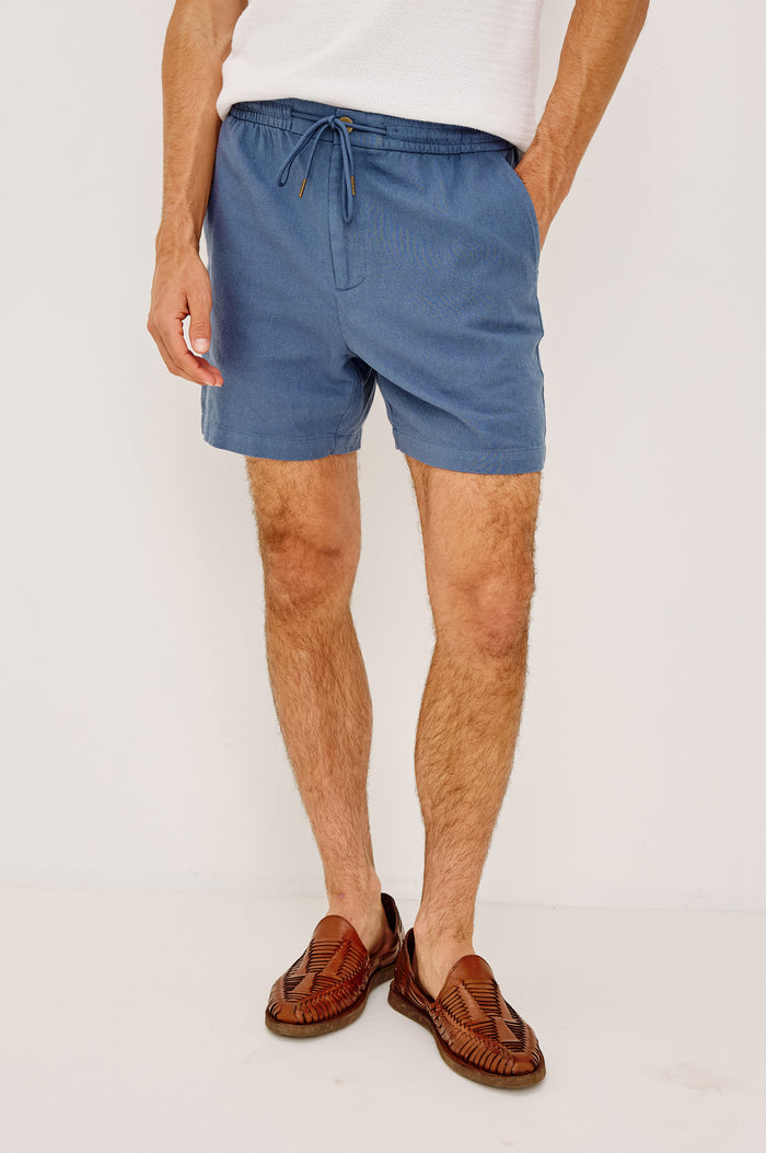 Archer Short in Cotton-Linen Blend With Relaxed Fit, Elastic Drawstring Waist, Front Zip Fly, Side Pockets, and Back Welt Pocket in Washed Blue Colorway - Lower Body Front View Featured on Model