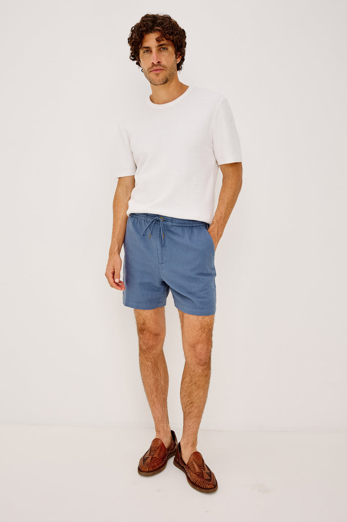 Archer Short in Cotton-Linen Blend With Relaxed Fit, Elastic Drawstring Waist, Front Zip Fly, Side Pockets, and Back Welt Pocket in Washed Blue Colorway - Full Body Front View Featured on Model
