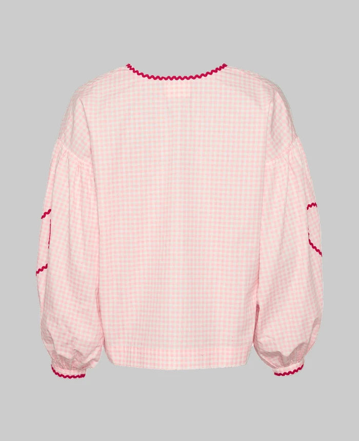 Back of pink checked blouse with long sleeves and red ric rac detail at cuffs and elbows.