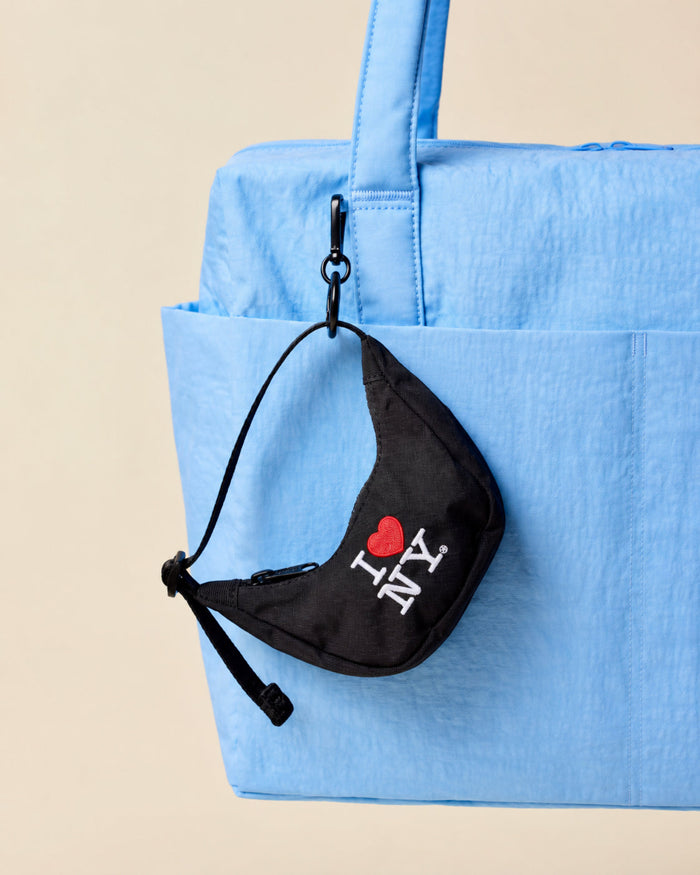 Black pouch with 'I ❤️ NY' text attached to a blue bag on a beige background