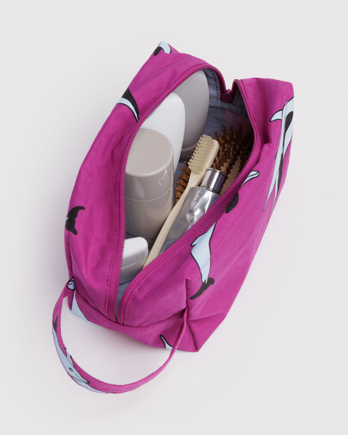 Pink toiletry bag with dolphin patern and items inside and carry handle