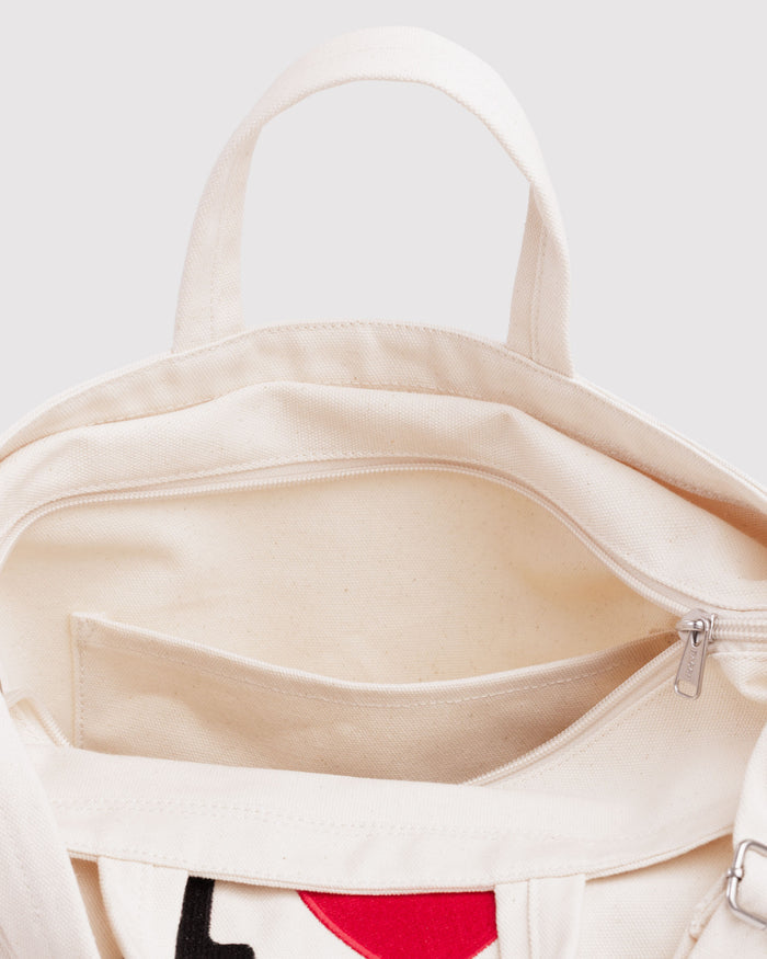 Close-up of a beige bag with a zipper and carry handle and adjustable shoulder strap.