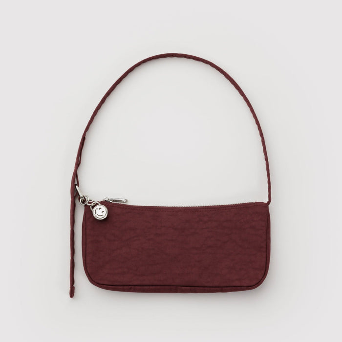 Mahogany handbag with a metal clasp to adjustable the shoulder strap and metal silver smiley face bag charm attached.