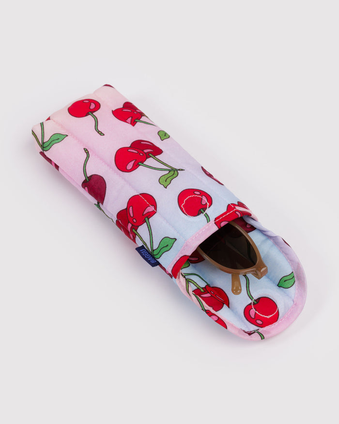 Puffy and quilted eyeglasses sleeve with cherry pattern on a light pink and blue background with sunglasses inside.