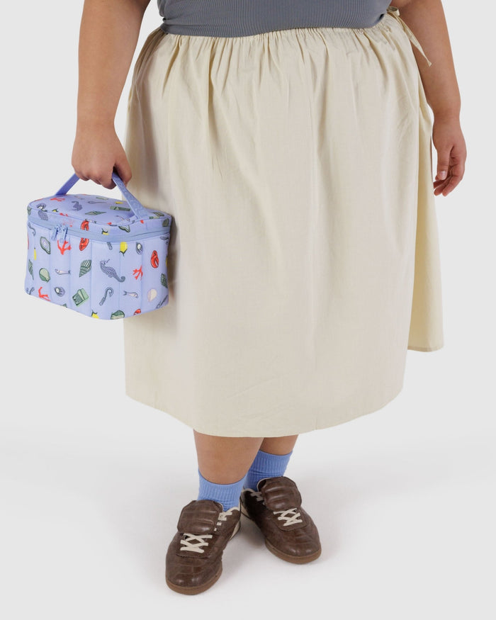 Person holding the handle on top of a puffy and quilted lunch bag in blue with sea charm prints - ANNIE.G