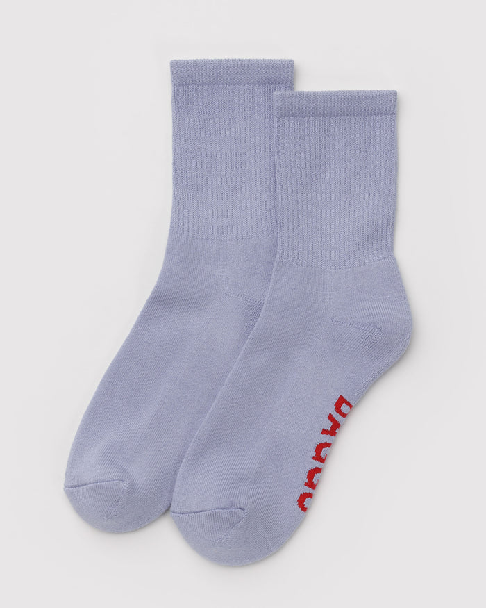 Pair of light blue ribbed crew socks with red Baggu logo on sole.