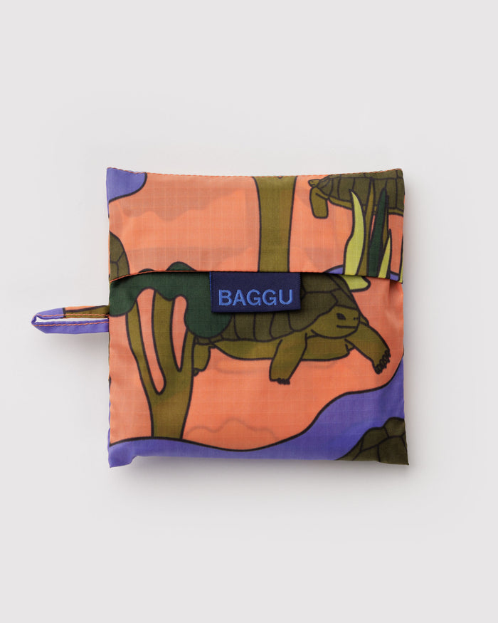 Folded reusable bag with turtle design and 'BAGGU' branding and hanging loop