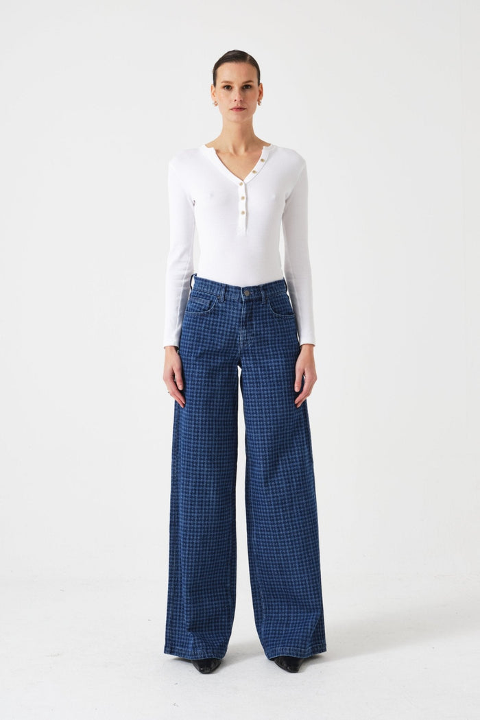 Woman wearing a white long-sleeve top and blue checkered pants