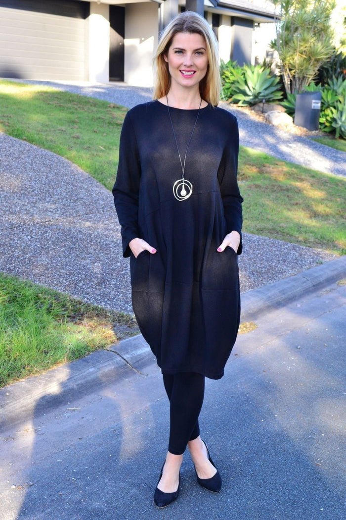 Black cocoon winter pocket tunic dress by Peony, featuring a relaxed fit, long sleeves, and functional pockets, shown on a model.