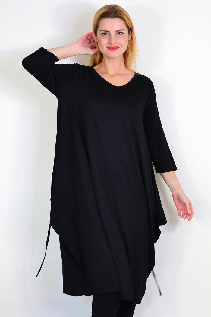Black relaxed oversized tunic dress by Lilia Whispers, featuring a loose fit and simple neckline, displayed on a hanger.