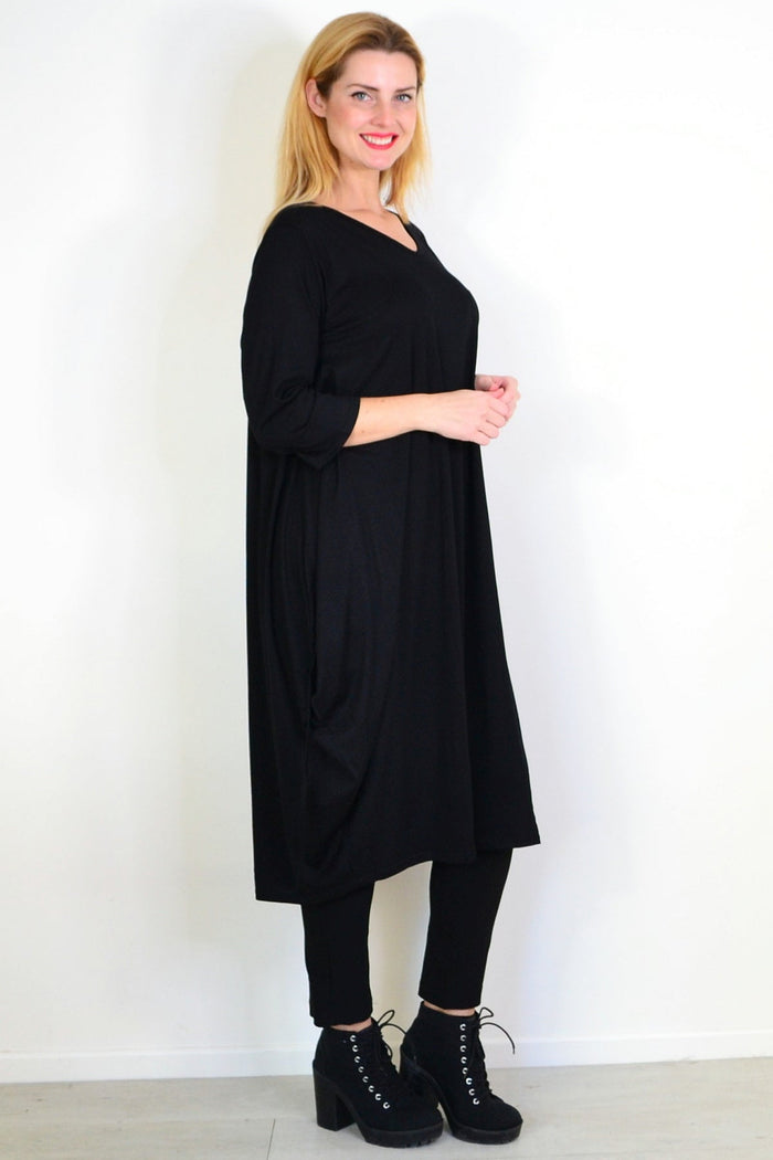Black Lilia Whispers relaxed oversized tunic dress displayed on a hanger, showcasing its loose fit and casual style.