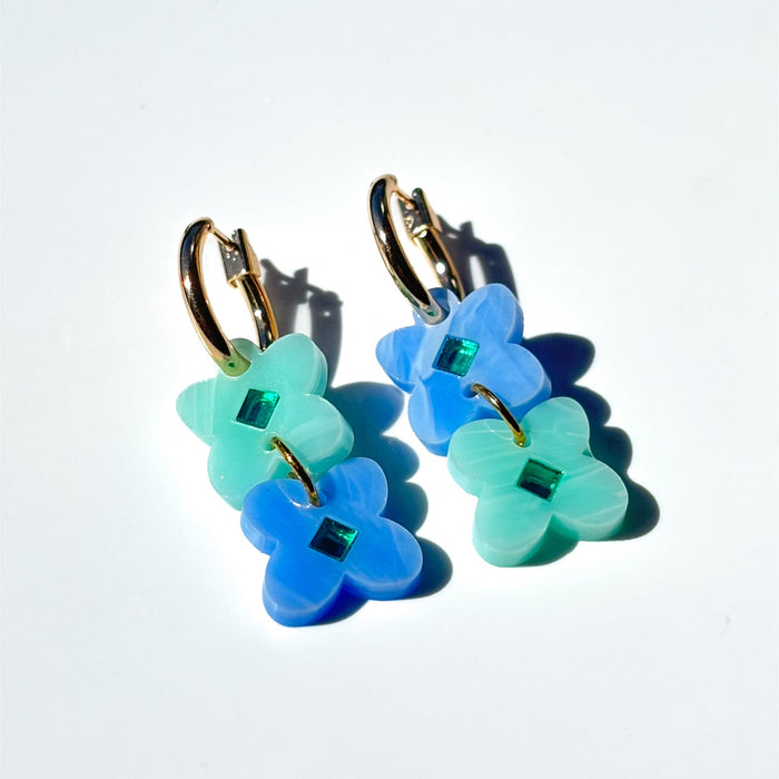 Two sweet clover acrylic flowers inset with gold mirror diamond in light green and blue swirl acrylic on small gold hoops.
