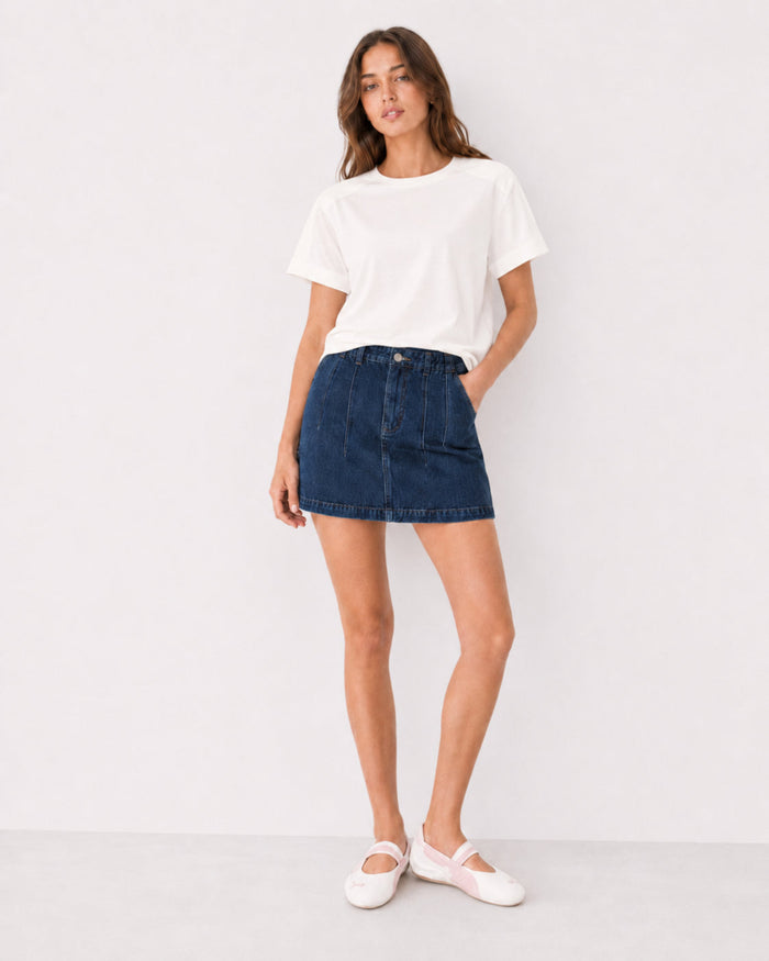 Woman wearing a white t-shirt and blue denim mini skirt.