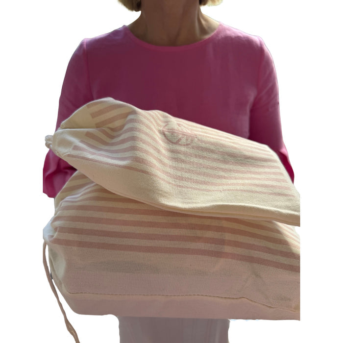 Woman holding two pink striped gift bags stacked.