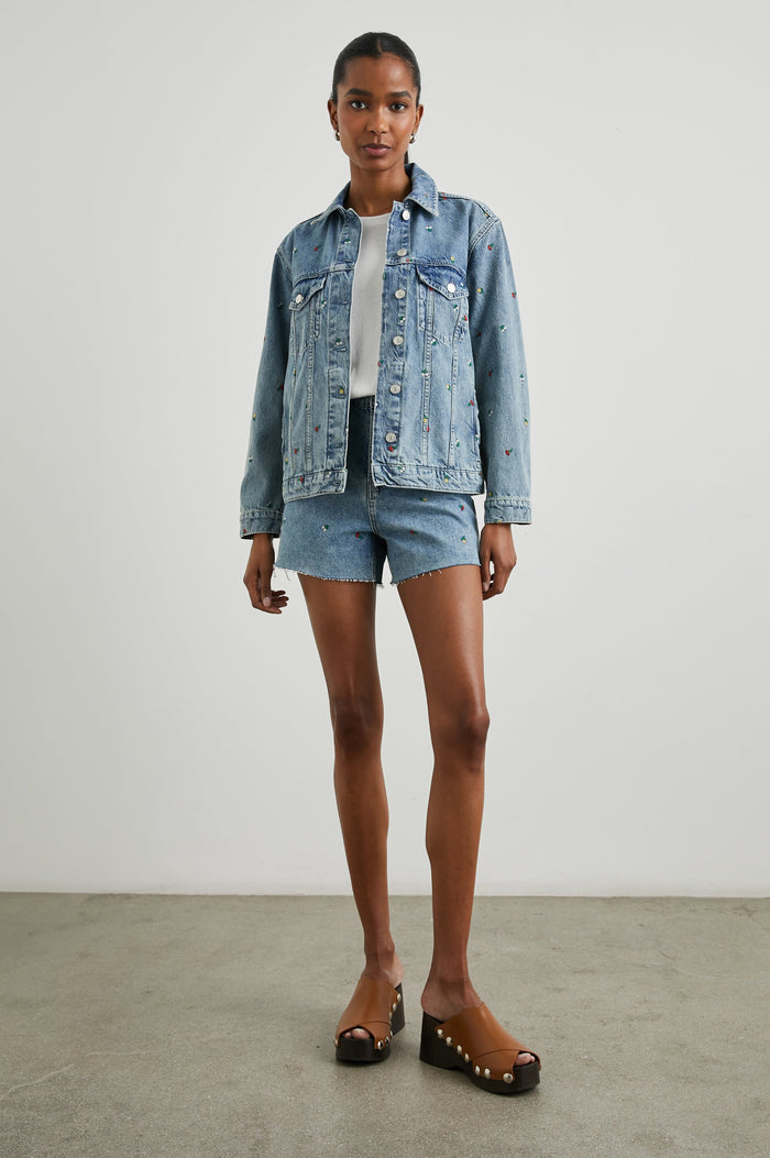 Grove Boyfriend Trucker Denim Jacket with Button Closure, Two Front Pockets, Two Chest Button Flap Pockets, Front Vertical Seams in Flower Field Colorway, with Embroidered Daisies in Yellow, Red and White - Front Full Body View Featured on Model