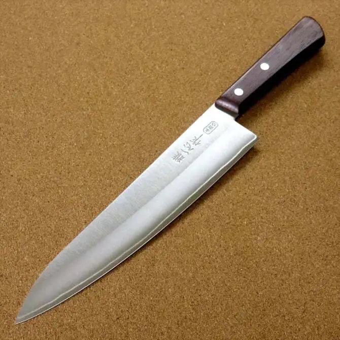A Kanetsugu Miyabi Issin Chef Knife with a focus on the blade's sharp edge on brown background.