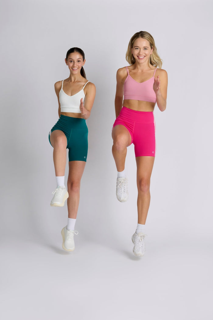 Two women exercising in bike shorts with sports bras and sandshoes.