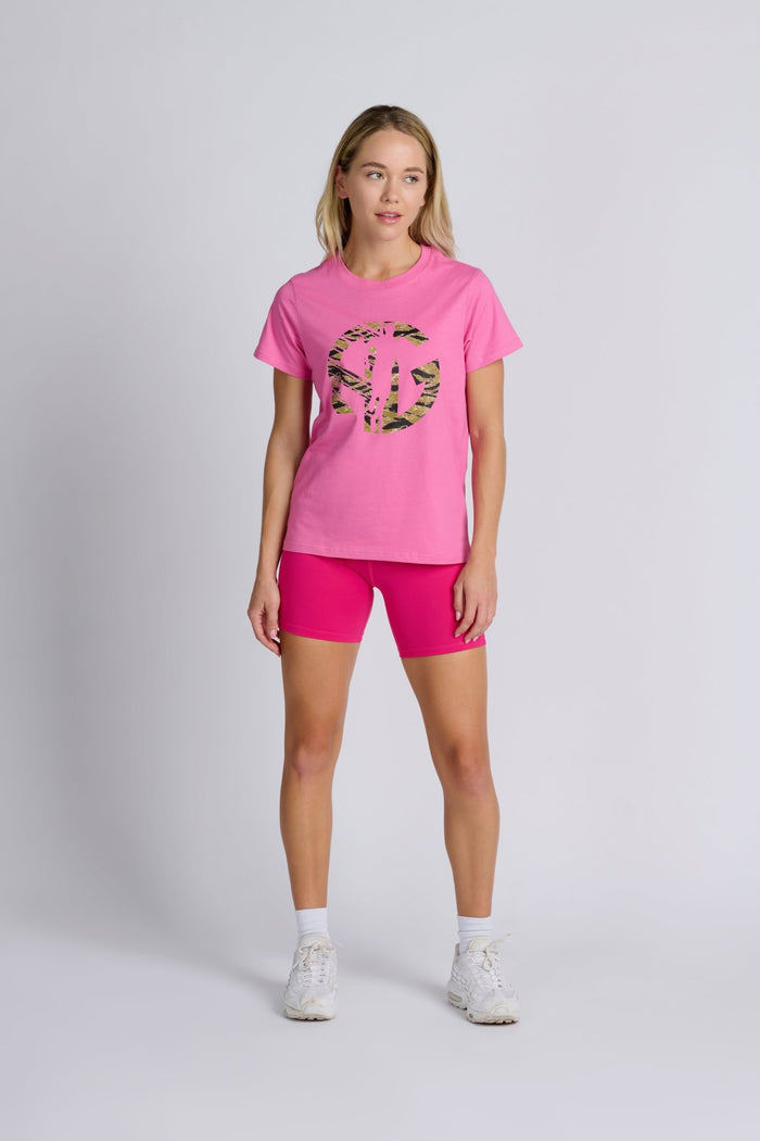 Woman wearing a pink tee with camo AG logo and pink bike shorts.