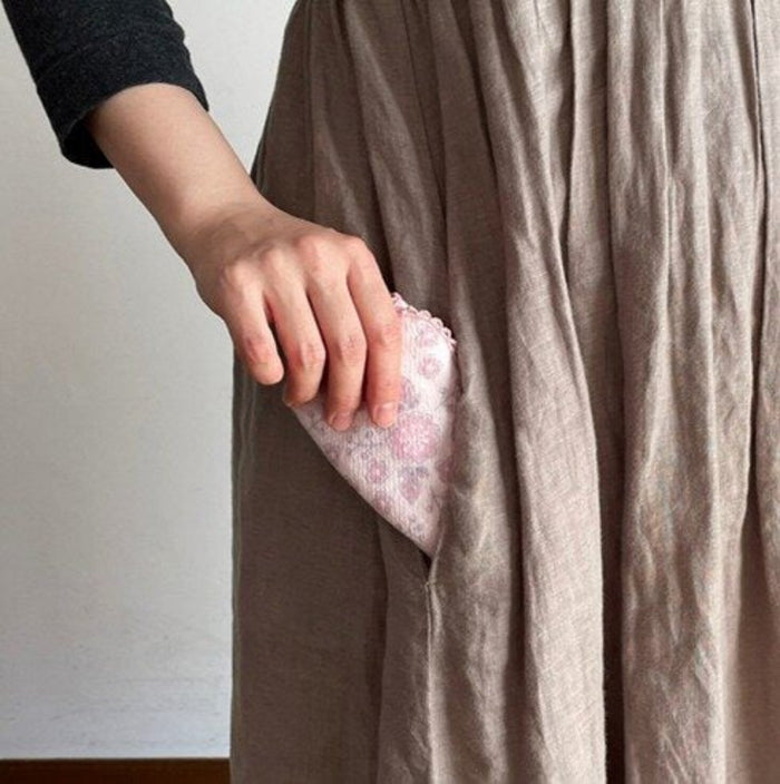 Person holding a pink face towel and placing inside a dress pocket.