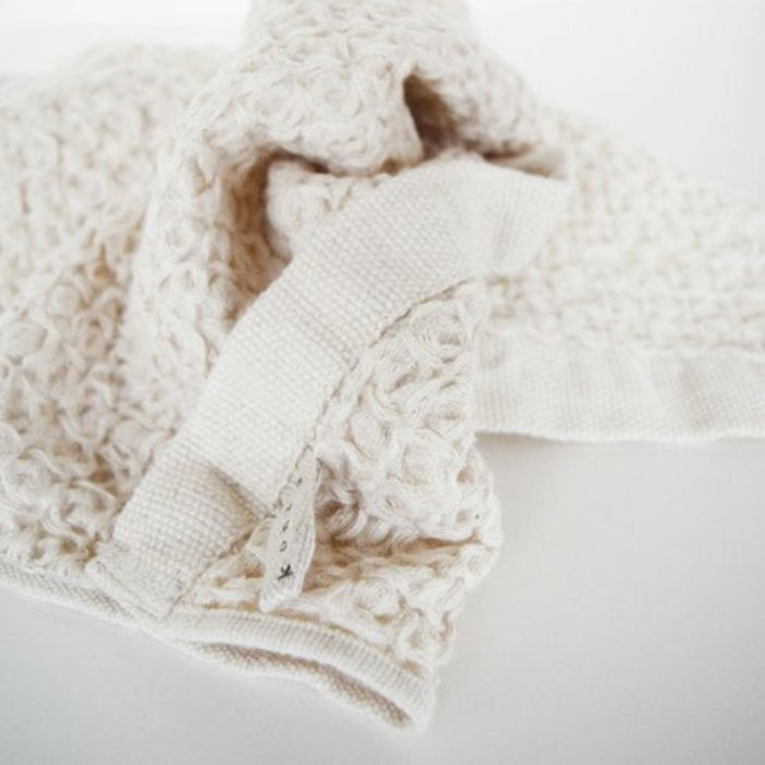 Close-up of a crumbled ivory towels waffle texture with tag.