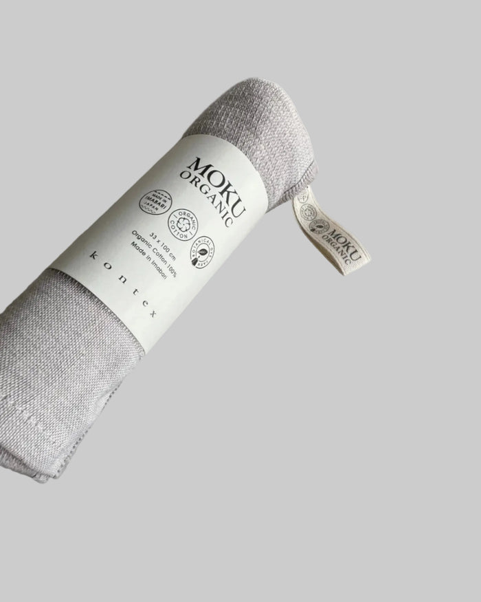 Light blue towel rolled up with 'Moku Organic' label.