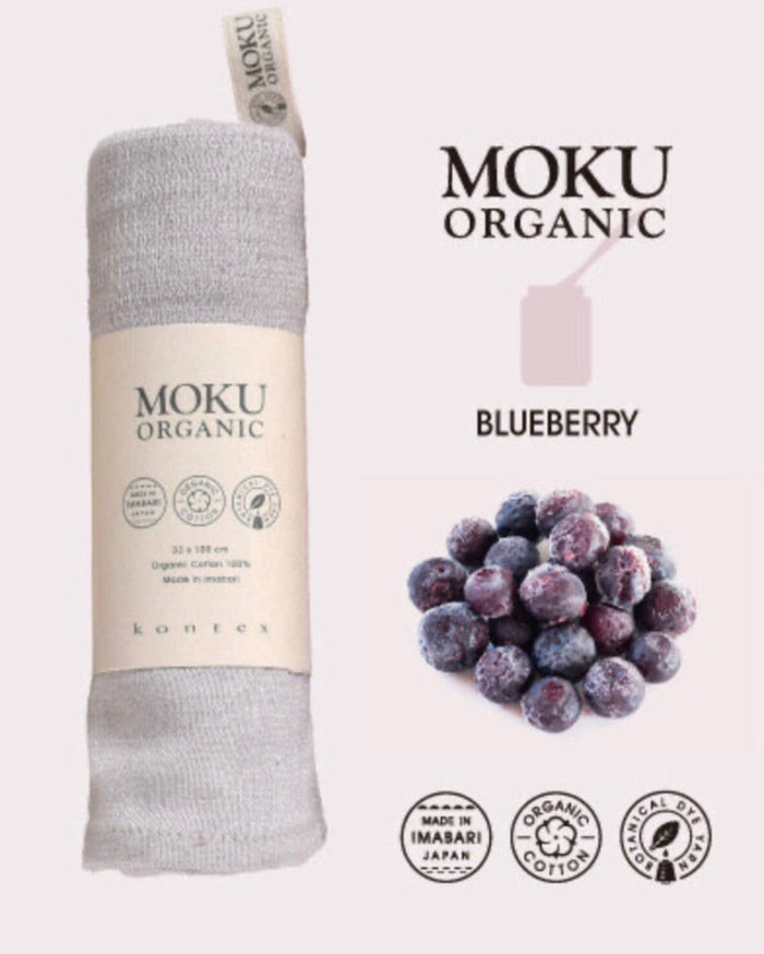 Moku Organic product wrapped in packaging next to blueberries on a blue background