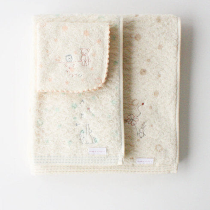 Cream baby washcloth in peach pink design sitting on top of baby towels.