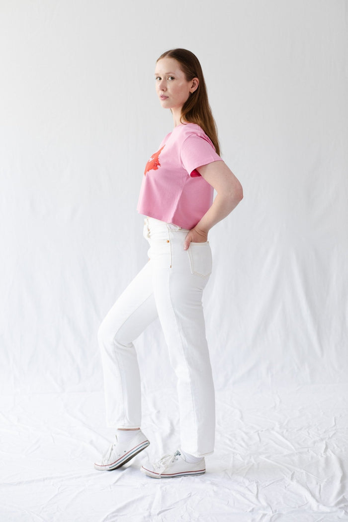 Side view of a woman wearing a pink cropped tee with short sleeves.