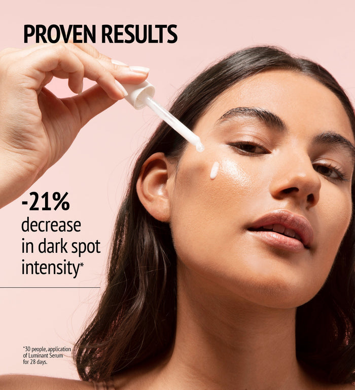 Close-up of a woman applying Luminant Serum | [ comfort zone ] to her cheek, highlighting skincare and visible brightening effects for reducing dark spot intensity.