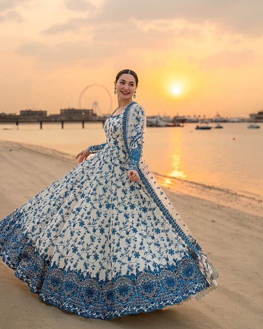 Model in a long white and blue embroidered pishwas maxi at the beach.