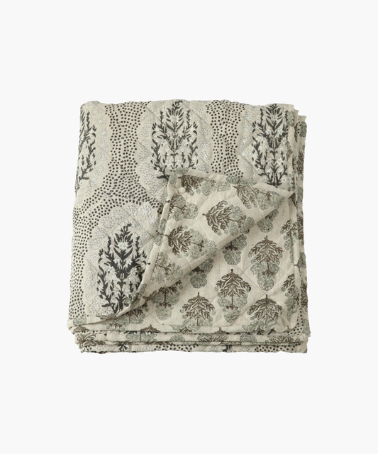 A folded quilt with a floral pattern in a neutral beige color. | Wildwood Home Co.