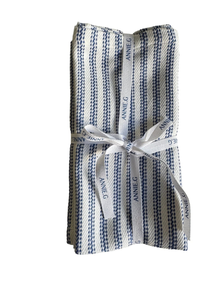 A set of 4 blue ticking cotton cloth napkins folded and wrapped in ribbon.