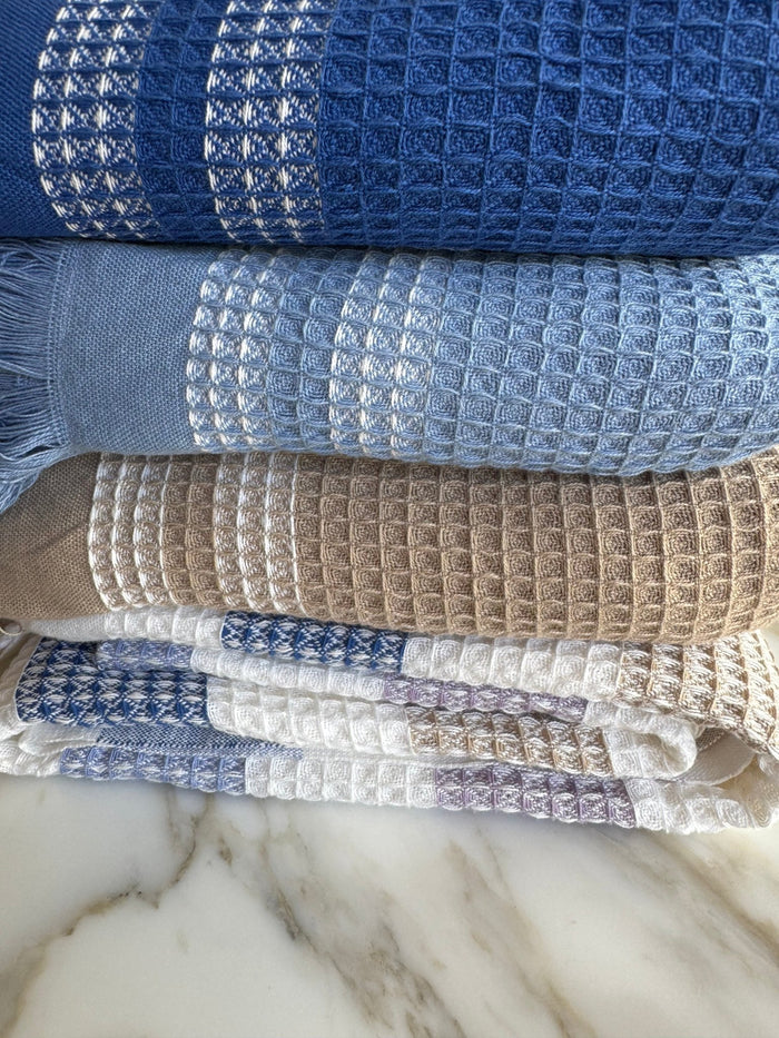 Stack of folded coloured handwoven waffle weave towels with border pattern - ANNIE.G