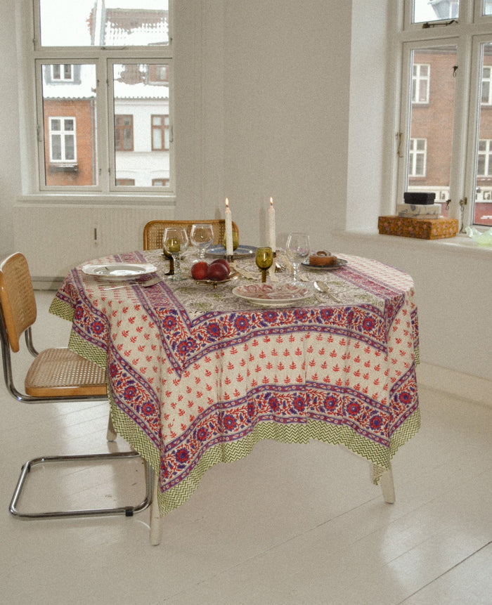 Green, pink and purple patterns on cream fabric cotton Tablecloth in Purple Flower on a round table.