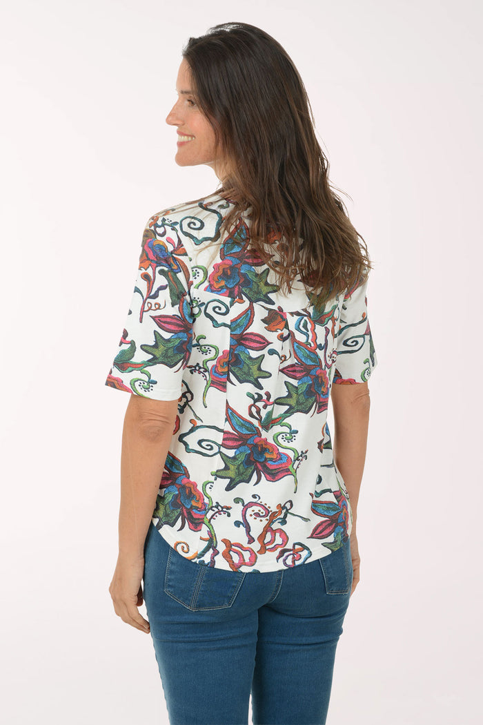 Woman wearing a colorful floral blouse and blue jeans on a white background