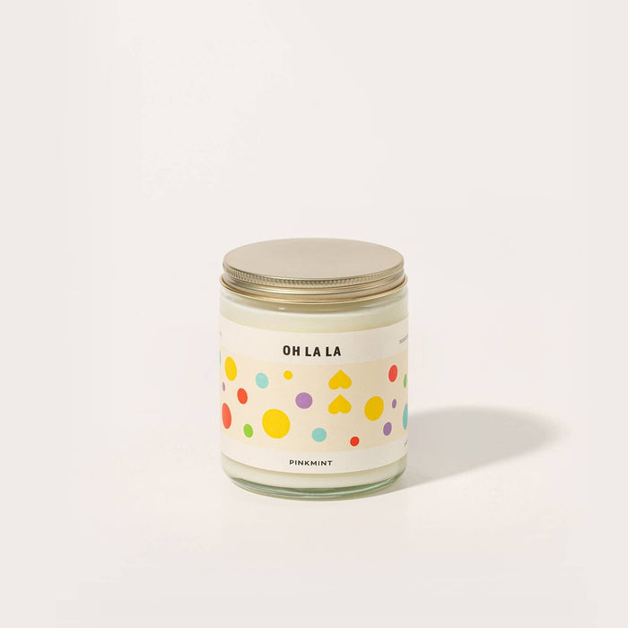 Glass jar with white candle inside, a metal lid and a colourful label - ANNIE.G