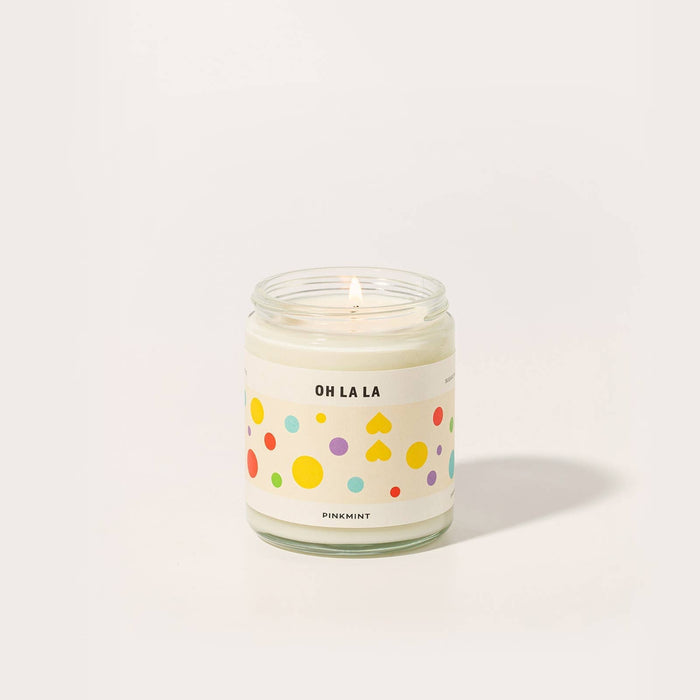 White candle in a glass jar with a wick and a colourful label - ANNIE.G