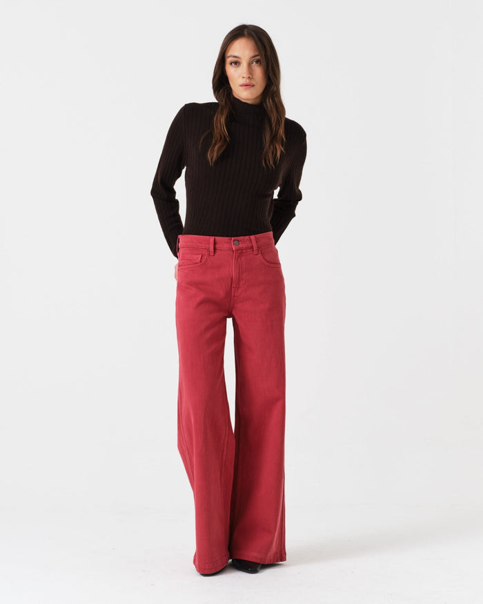 Woman wearing a black top and faded rose denim jeans.