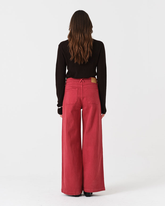 The back of a woman wearing faded rose wide-leg denim jeans and a black top.